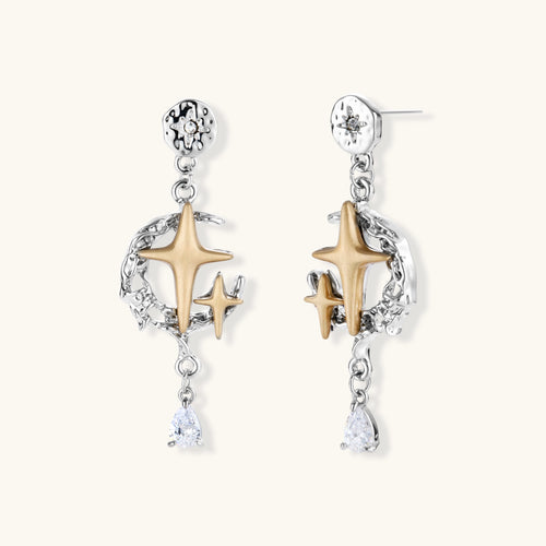 Two-tone star earrings with gold celestial motifs, silver chains, and clear crystal droplets on white background.